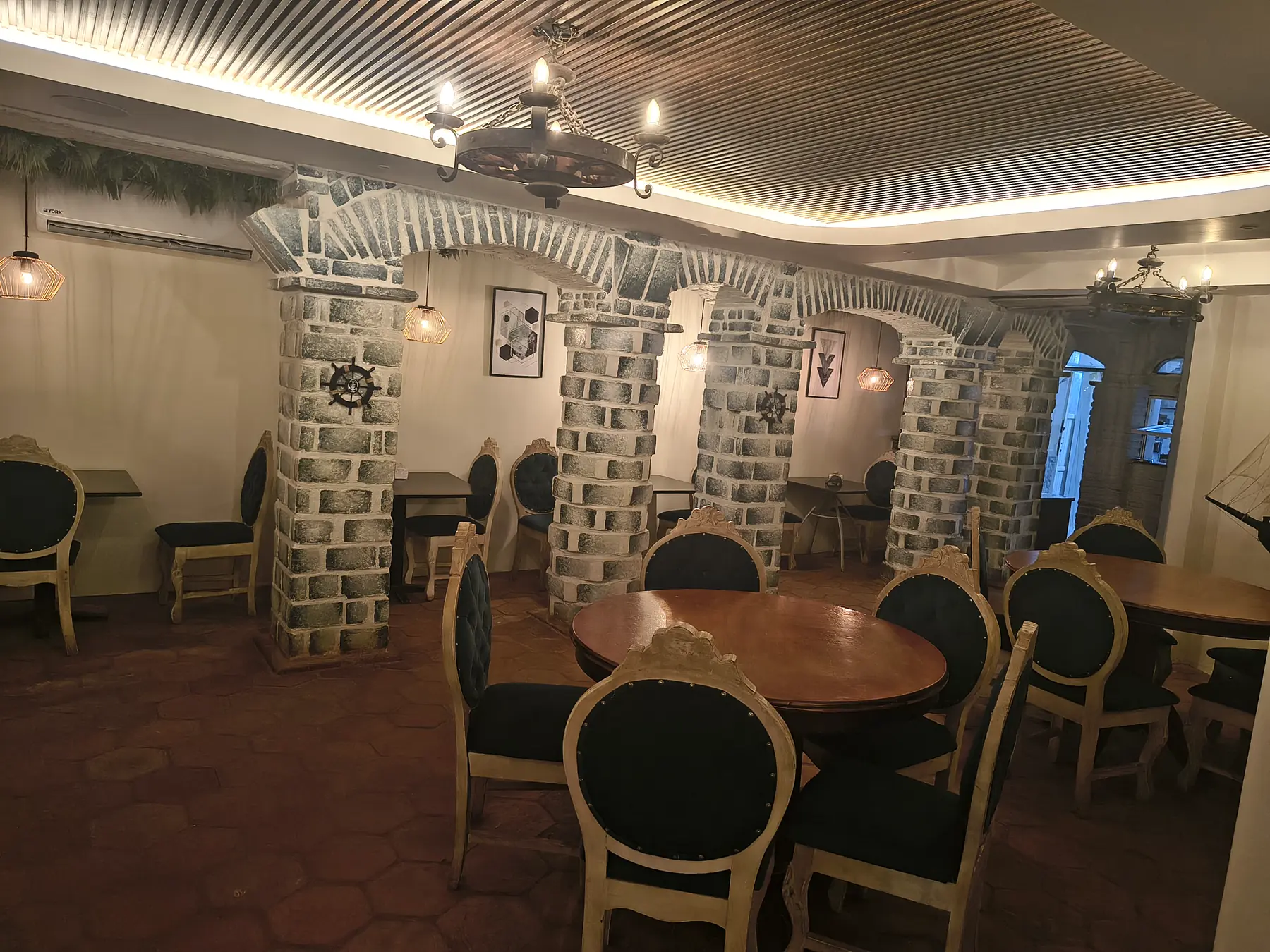 Salón de La Camaronería: arcos de ladrillo, mesas redondas de madera y lámparas de hierro