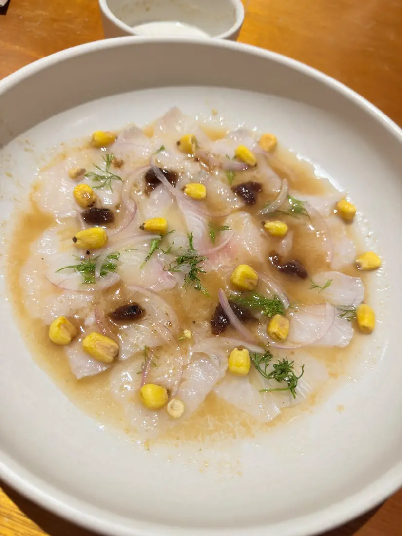 Tiradito de pesca del día con maíz, cebolla morada y eneldo